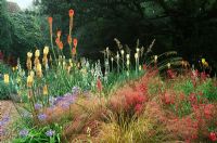 Stone garden with Stipa Arundinacea, Agapanthus Cultivars, Penstemon 'Garnet', the tall spikes of Kniphofia uvaria 'Nobilis', Kniphofia 'Tawny King', Kniphofia 'Ice Queen' and Galtonia Candicans, Holbrook garden, Devon