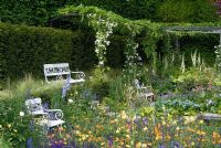 Garden inspired by Karl Foerster. White seats, steel pergola with Rosa 'Bobby James', Geum 'Prinses Juliana', Aquilegia chrysantha 'Yellow Queen', Salvia x sylvestris 'Mainacht'.  The Daily Telegraph Garden, RHS Chelsea 2007