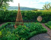 Detail of a decorative vegetable garden, with a willow obelisk and box edged beds.
