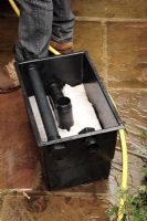 Pond maintenance - step 9 cleaning pond filter of pond sludge, replacing cleaned filter material over plastic casings