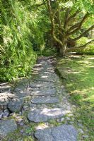 Path made from large stone slabs and cobblestones leading through Japanese garden - The Gardens at Norrviken
