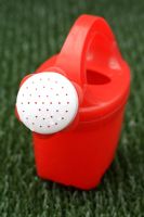 Child's plastic watering can on astroturf lawn
