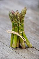 Asparagus tied with twine on weathered wooden surface