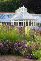 Glasshouse and perennial planting in The Walled Garden at Scampston Hall, Yorkshire, designed by Piet Oudolf. Planting includes Origanum 'Rosenkuppel' and  Monarda 'Scorpion'