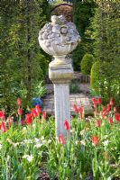 Stone plinth ornament with Tulipa 'Red Shine' beneath