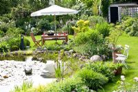 Seating area overlooking pond in large suburban garden