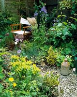Mixed herbaceous beds with gravel pathway leading to director's chair in quiet corner of the garden