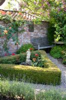 Mediterranean garden with triangular bed of Roses, edged with Buxus and Lavandula in foreground