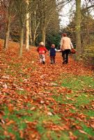 Children and adult amongst falling leaves of autumn