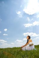 Woman sitting in field with suncream in shape on sun on her arm