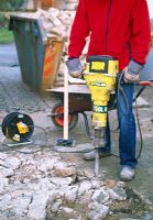 Man using pneumatic drill to break up old concrete of driveway