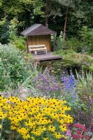 Wildlife pond and gazebo at Honeybrook House Cottage, Worcestershire - Planting includes Rudebckia 'Goldsturm', Verbena bonariensis, Sedum, Delphinium, Phormium tenax and Photinia 