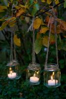 Tealights in jam jars with string hanging from branches
