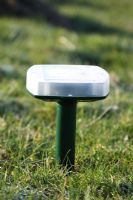 Sound emitting mole scarer positioned in lawn