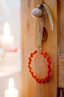 Christmas decoration made from red Pyracantha berries hung from cupboard door with gingham ribbon