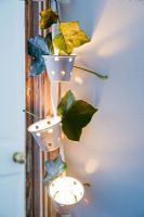 Tealight holders decorated with ivy leaves hanging on door frame