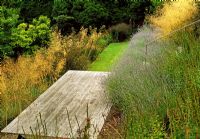 Half way down a steep slope the ground is levelled to create this deck for entertaining. Lavender and Stipa gigantea soften the edges.