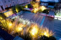 Decked terrace at night with pink and white led lighting and blue glass gravel - Roof garden, Holland Park, London