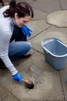 Lady cleaning patio surface with stone cleaner and brush - Brushing diluted cleaner into surface