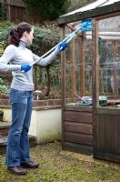 Cleaning greenhouse glass using a long handled squeegee