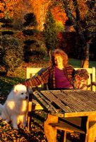 Louise Bendall with dogs 'Berkeley' on left, and 'Blue' in the garden at sunset - Highfield Hollies, Liss, Hampshire