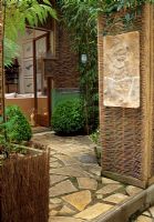 Small Paris garden with woven screens creating an entrance and enclosing the garden, plants include box, tree fern and bamboo
