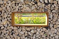 Window in wall of logs with view of Spring garden beyond