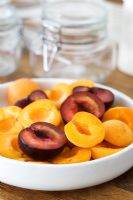 Plums variety 'Angeleno' and apricots halved in bowl prepared for making into jam
