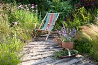 Deck chair in coastal-look garden, with trug and container with Nepeta