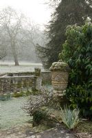 Stone urn and balustrades leading down to the river, Heale House Gardens, Wiltshire, in frost