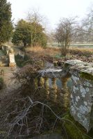 Stone steps and balustrades with Cotoneaster, leading down to river, Heale House Gardens, Wiltshire in frost