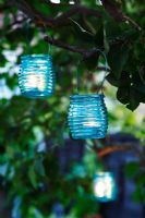 Turquoise glass tealight holders hanging in tree