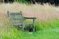 Garden bench on the lawn grass border at Waterperry Gardens, Oxfordshire, England