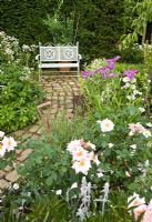 Perennial borders with brick path leading to ornate white bench - Wilkins Pleck, NGS, Whitmore near Newcastle-under-Lyme in North Staffordshire 
