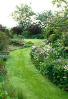 Mown strip of lawn takes a curving path along the colourful border towards the front door.