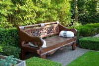 Carved Indonesian bench backed by Bamboo