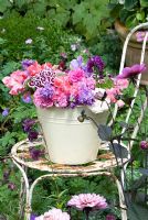 Cream bucket filled with scented summer flowers - Mattiola incana, Dianthus barbatus, Lathryus odorata on vintage chair