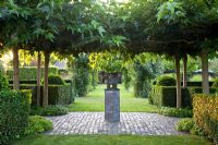 Formal garden with focal point under canopy of Morus alba - Mulberry trees. Hedges of Taxus and Prunus lusitanica