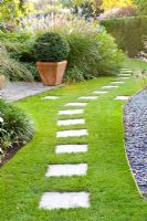 Stepping stone path over lawn with slate chipping edging.