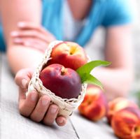 Woman holding nectarines in a basket
