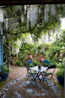 Mosaic tiled patio under the shade of a pergola with Wisteria climbing on it. No. 11, Christchurch, New Zealand