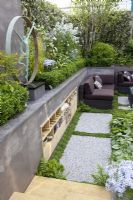 Sunken patio area with storage built into wall of raised bed and wicker furniture. 'A Joy Forever' Garden, Silver medal winner at RHS Chelsea Flower Show 2010 