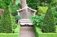 Seat at end of back garden with low Buxus - Box hedge and Pyramids of Taxus - Yew. Mathern House, Mathern, Monmouthshire, Wales. Early June. Garden opens for National Gardens Scheme. 