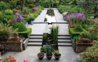 A beautiful garden in Dublin. Colourful borders and topiary. Galvanised metal containers with Allium 'Purple Sensation' and Ornamental Grasses. Iris siberica in terracotta pots. Rectangular pond inspired on the garden of Alhambra in Granada, Spain