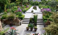 Elevated view of The Dillon Garden, Dublin, Ireland. Topiary pyramid. Iris siberica in terracotta pots. Allium 'Purple Sensation'and Galvanised metal containers with Alliums and Ornamental Grasses. Rectangular pond inspired by the garden of Alhambra in Granada, Spain.