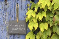 Slate sign on door, reading 'I'm in the garden' 