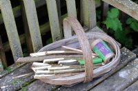 Garden seat with wooden trug of hazel stick markers, garden twine and seeds 