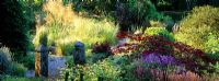 A gravel path leads through perennials, grasses, shrubs and trees in the garden at Pinsla Lodge, Cornwall