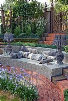Tiled outdoor seating area with wooden lamps surrounded by a herringbone path, plants include Agapanthus 'Blue Cloud', Lavandula angustifolia 'Alba', Koeleria glauca and Armeria maritima 'Alba'. 'The Garden Lounge' - Silver Gilt Medal Winner - RHS Hampton Court Flower Show 2010 
 