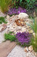 Bubbling stone water feature, crushed recycled ceramic gravel path with sleepers edged with Thymus serphyllum 'Russetings' and Rosmarinus officinalis Prostratus Group - 'The Fire Pit Garden', Silver Medal Winner, RHS Hampton Court 2010